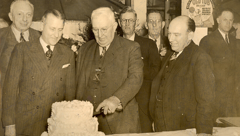 Membros da família cortando o bolo na festa de 4 anos de Jim Beam - 26 de março de 1939.