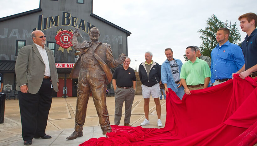 Fred Noe, da sétima geração de mestre destiladores de Jim Beam, e seu filho, revelam uma estátua em tamanho real do lendário destilador James B. Beam na Jim Beam American Stillhouse em Clermont, Kentucky.